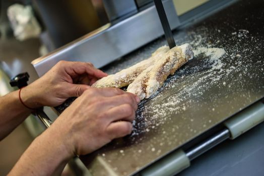 Close-up of male butcher cutting ham bones in a cutting machine inside a butcher shop.