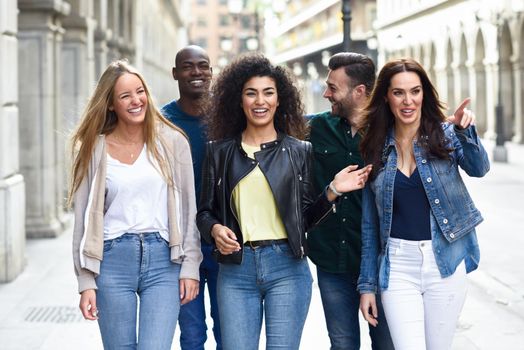 Multi-ethnic group of young people having fun together outdoors in urban background. group of people walking together