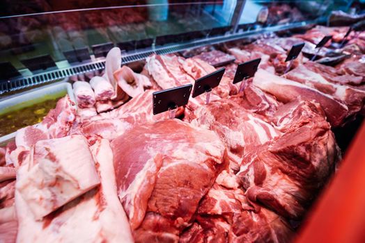 Fresh raw red meat at the butcher in refrigerated display