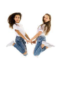 Two cheerful little girls have fun jumping in the studio on a white background.
