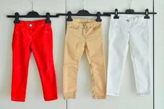 A row of baby trousers hang on a hanger