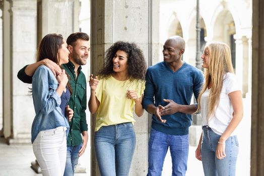 Multi-ethnic group of young people having fun together outdoors in urban background. group of beautiful women and men laughing together