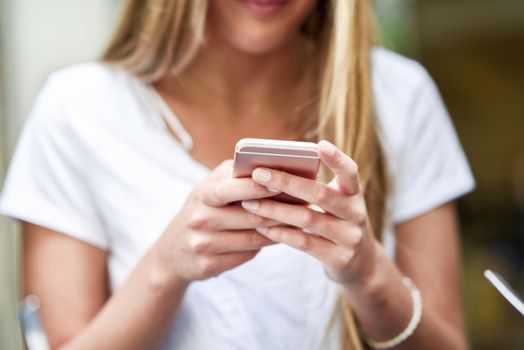 Close-up image of young blonde girl texting with smartphone, female hands typing text message via cellphone, social networking concept