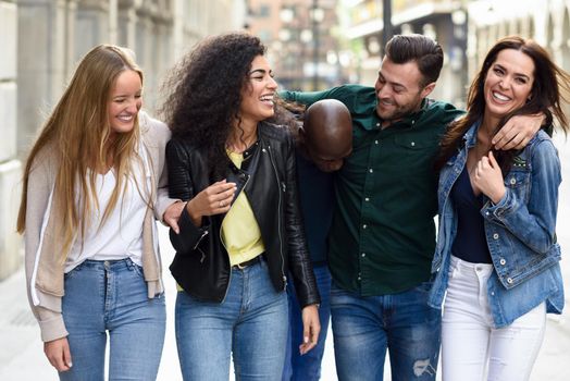 Multi-ethnic group of young people having fun together outdoors in urban background. group of people walking together