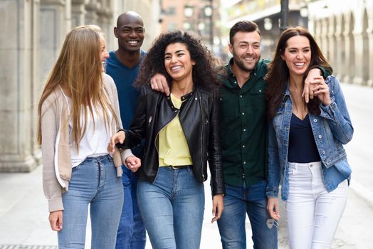 Multi-ethnic group of young people having fun together outdoors in urban background. group of people walking together