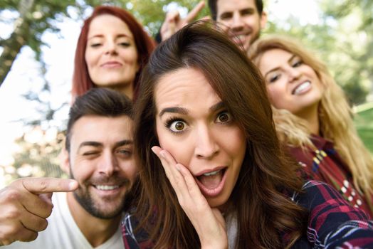 Group of young people together outdoors in urban background. Women and men sitting on stairs in the street wearing casual clothes.