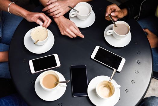 Top view of hands with coffee cups and smartphones on table in a urban cafe.