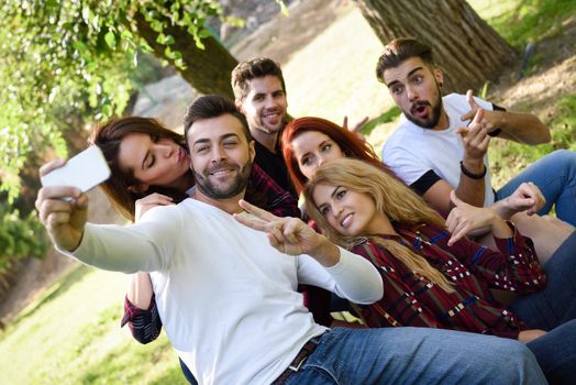 Group of friends taking selfie in urban park. Five young people wearing casual clothes.