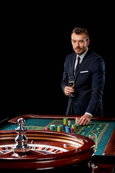 man in a suit playing roulette. addiction to gambling. In the hands of a glass. He bets chips
