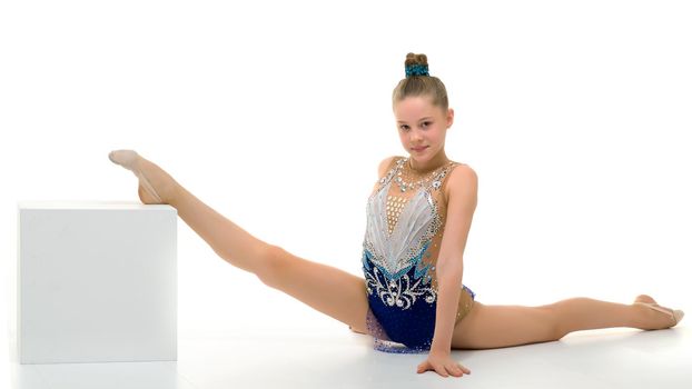 An elegant little girl gymnast in a beautiful sports swimsuit performs a gymnastic element, twine, on Big White Cuba. Separately on a white background.