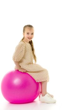 Beautiful little girl is playing with a big ball for fitness. Sports concept, happy childhood. Isolated over white background.
