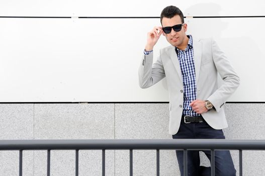 Portrait of a young handsome man, model of fashion, wearing tinted sunglasses