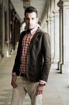 Portrait of a young handsome man, model of fashion, wearing jacket and shirt in urban background