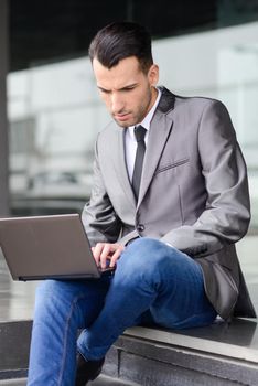 Portrait of attractive young businessman typing in a laptop computer in office building