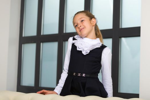 Cute little girl in school uniform near a large panoramic window.