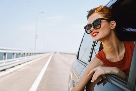 a woman is driving in a car on the road and looking out of the window. High quality photo