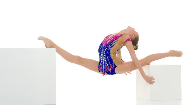 An elegant little girl gymnast in a beautiful sports swimsuit performs a gymnastic element, twine, on Big White Cuba. Separately on a white background.