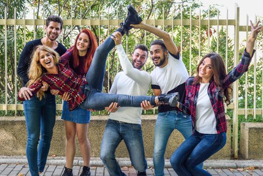 Group portrait of boys and girls with colorful fashionable clothes holding friend. Urban style people having fun - Concepts about youth and togetherness.