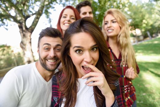 Group of young people together outdoors in urban background. Women and men sitting on stairs in the street wearing casual clothes.