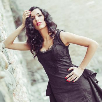 Portrait of beautiful woman, model of fashion, wearing black dress with curly hair. Spanish style