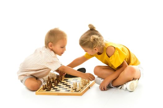 Couple boy and girl playing a board game of chess, thinking about the action and sitting on the floor. isolated on white background.