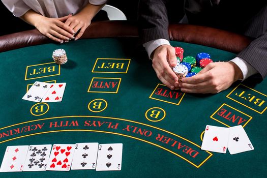 couple playing poker at the table. The blonde girl and a guy in a suit. close up hands. take chips won