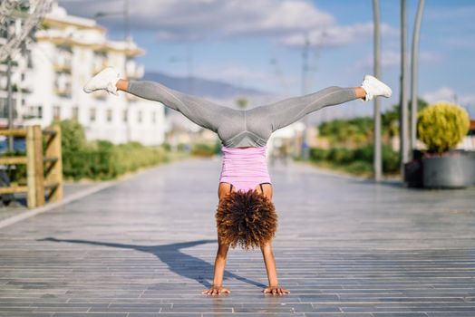 Black fit woman doing fitness acrobatics in urban background. Young female exercising and working out hard.