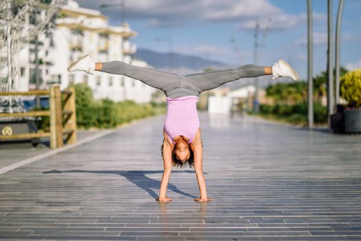 Black fit woman doing fitness acrobatics in urban background. Young female exercising and working out hard.