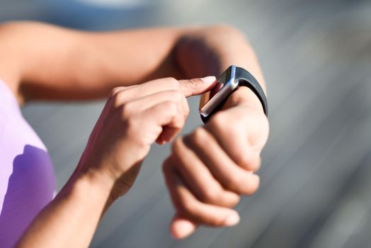Woman using smartwatch touching touchscreen in active sports activity. Close-up of hands and wrist with smart watch screen.