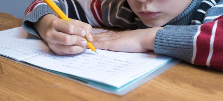 Focused first grader learning to write and doing homework.