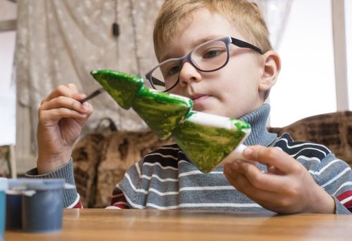 A seven-year-old boy paints a Styrofoam Christmas tree green in preparation for Christmas. Handmade Christmas Gift Ideas