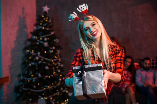 Christmas, x-mas, New year, winter, happiness concept - smiling woman in santa helper hat with gift box. Funny people. Christmas party at home