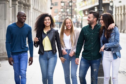 Multi-ethnic group of young people having fun together outdoors in urban background. group of people walking together