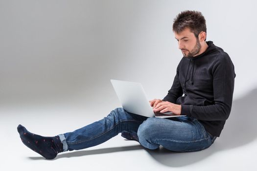 a young man in casual clothes working on a laptop.