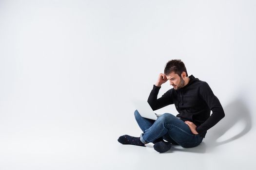 a young man in casual clothes working on a laptop. upset looking at monitor