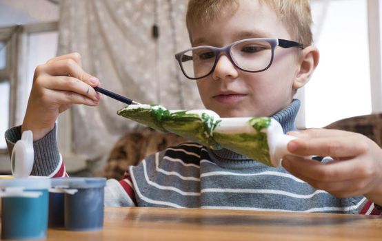 A seven-year-old boy paints a Styrofoam Christmas tree green in preparation for Christmas. Handmade Christmas Gift Ideas