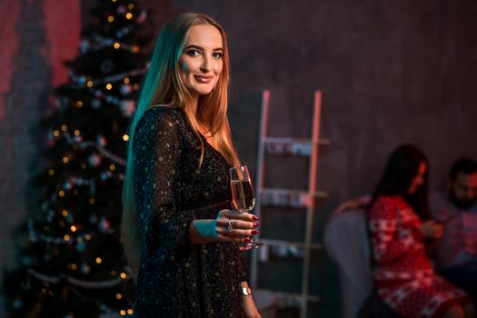 Beautiful young woman with glass of champagne at Christmas party. Funny people.