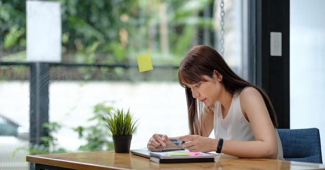 Young Asian girl using smartphone buying online shopping by credit card at home. Lifestyle woman at house concept.