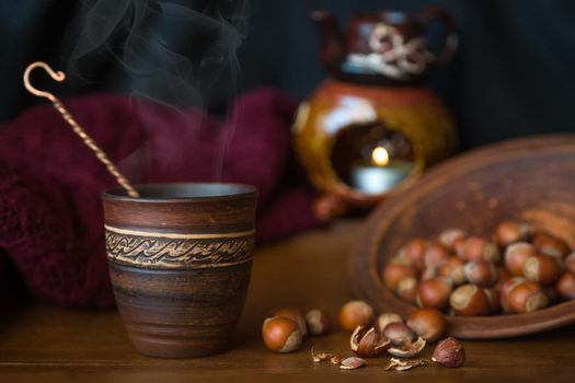 Dark background with a hot drink in a ceramic Cup and the scattered nuts hazelnuts on a wooden surface.