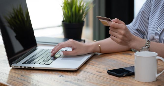 Close up hand of asian woman buying online with laptop computer and credit card at home.