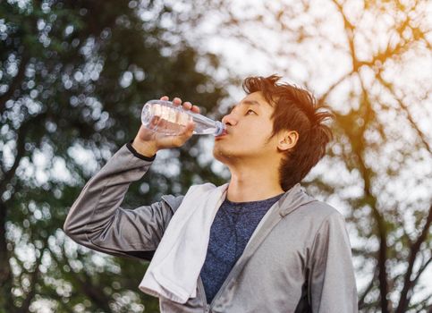 young sporty man drinking water in the park