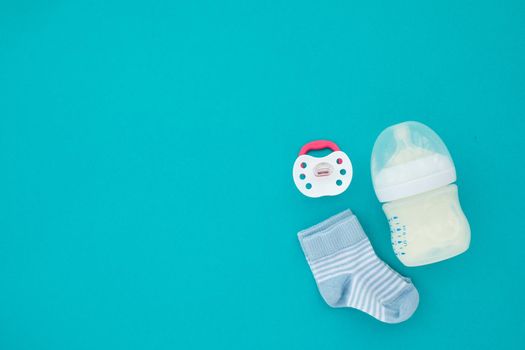 Set for a newborn nipple bottle and socks blue background top view