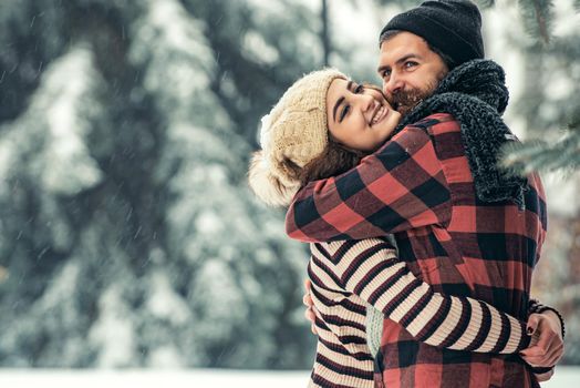 Winter happy couple in love embrace in snowy cold forest, winter holiday love and relations