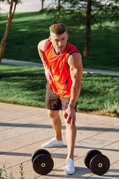 sporty man in the morning in the park with dumbbells exercise. High quality photo