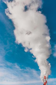 Environmental pollution, environmental problem, smoke from the chimney of an industrial plant or thermal power plant on a background of blue sky with clouds.