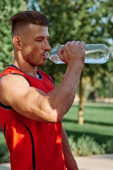 athletic man with dumbbells in his hands outdoors in the park. High quality photo