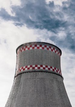 Cooling tower of an industrial plant or thermal power plant against a blue sky.