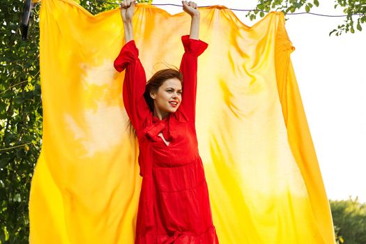 beautiful woman posing in red dress outdoors yellow cloth. High quality photo