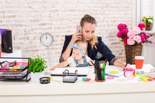 Family Business - telecommute Businesswoman and mother with kid is making a phone call. At the workplace, together with a small child