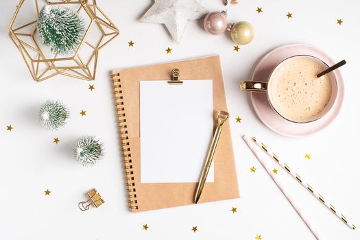 Desktop blank note pad. Flat lay of white working table background with cup of coffee and Christmas decoration. Top view balls, fir tree, paper clips, mock up greeting card, craft Notebook and pen.